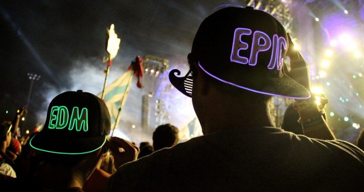 Neon hats being worn in a crowd with letters EDM and word EPIC on the back
